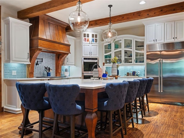 kitchen with white cabinetry, premium range hood, appliances with stainless steel finishes, and tasteful backsplash