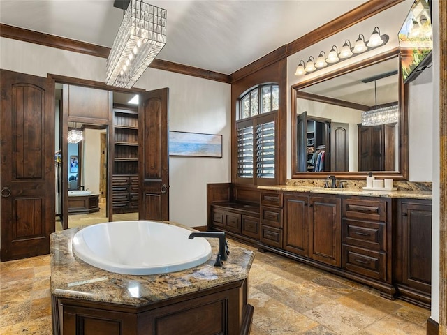 bathroom with a bathing tub, vanity, ornamental molding, and an inviting chandelier