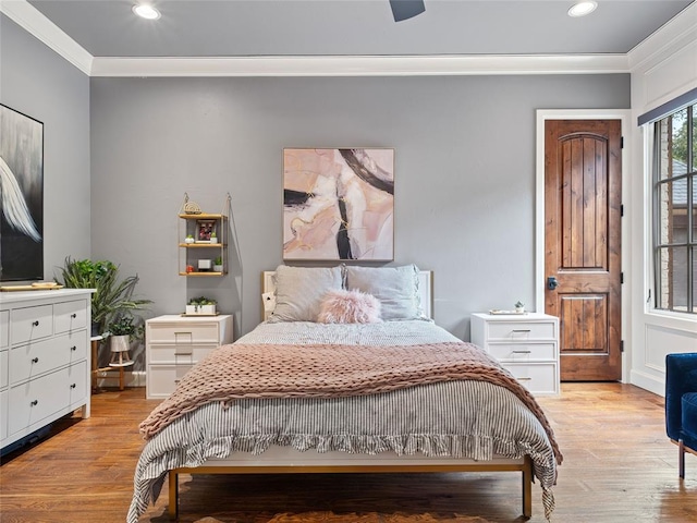 bedroom featuring ceiling fan, ornamental molding, and light hardwood / wood-style flooring