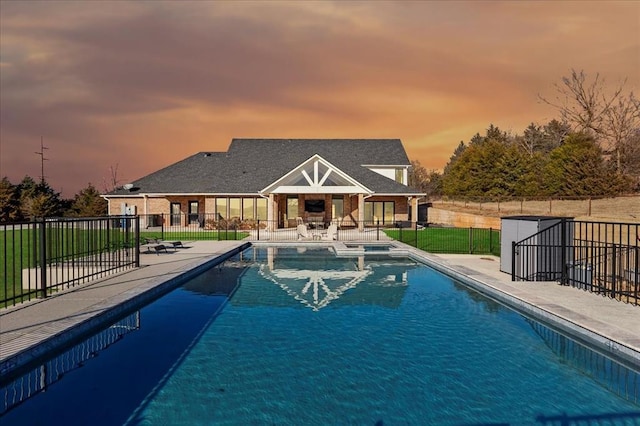 pool at dusk with a patio area and an outdoor structure