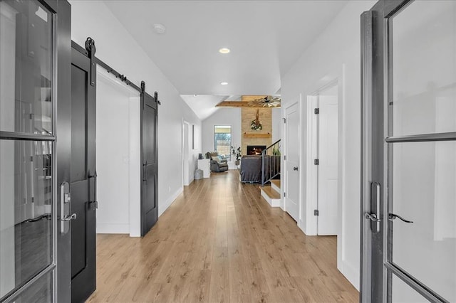 hallway featuring lofted ceiling and light hardwood / wood-style flooring