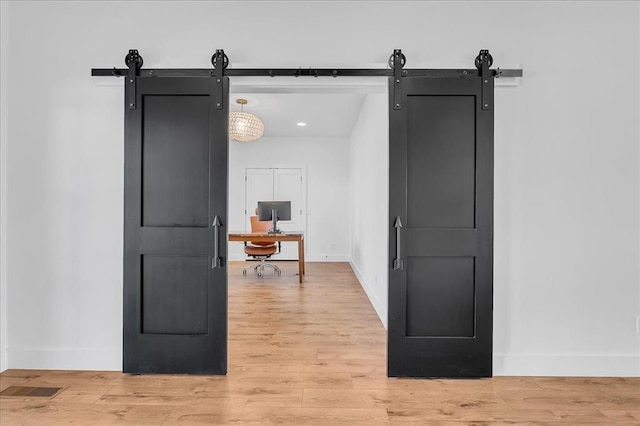 corridor with a barn door and hardwood / wood-style floors