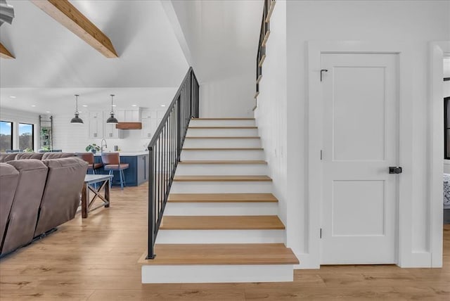 staircase with beamed ceiling and wood-type flooring