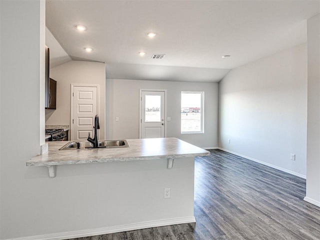 kitchen with lofted ceiling, sink, a breakfast bar, and kitchen peninsula