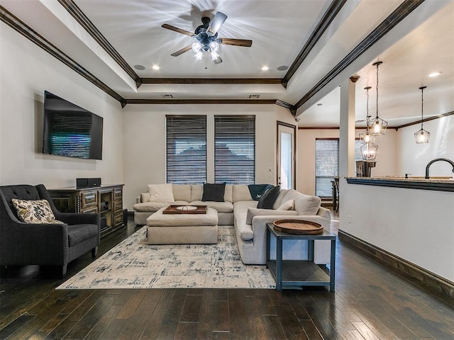 living room featuring ornamental molding, a raised ceiling, ceiling fan, and dark wood-type flooring