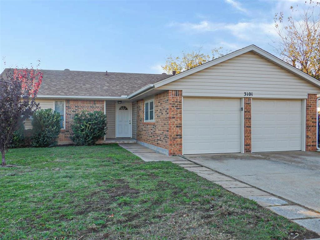 ranch-style house featuring a garage and a front lawn