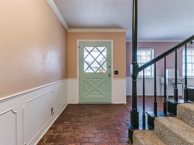 entrance foyer with crown molding and a healthy amount of sunlight