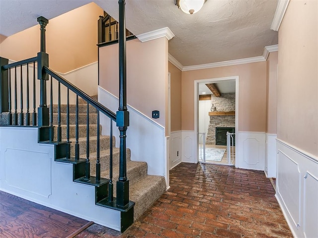 stairway featuring ornamental molding and a fireplace