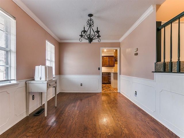 unfurnished dining area with crown molding, dark hardwood / wood-style flooring, and an inviting chandelier