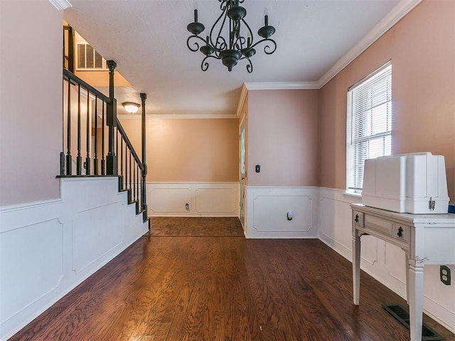 foyer with crown molding, dark hardwood / wood-style flooring, and a chandelier