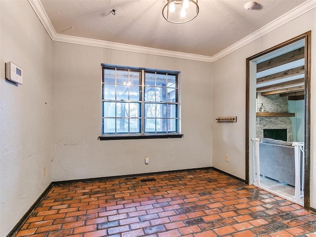 spare room with a textured ceiling, a fireplace, and crown molding