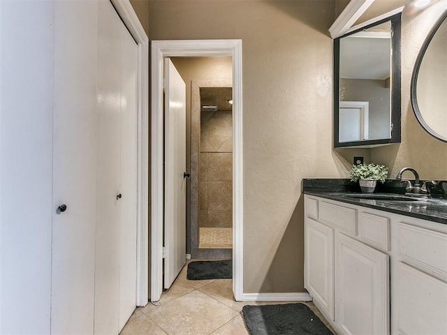 bathroom featuring tile patterned flooring, vanity, and tiled shower