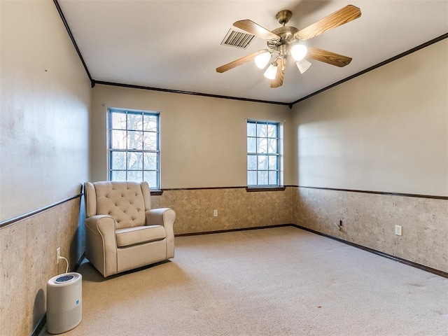 living area featuring light carpet, wooden walls, ceiling fan, and ornamental molding