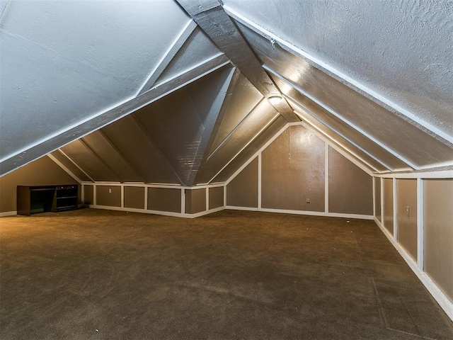 bonus room with a textured ceiling, dark carpet, and lofted ceiling