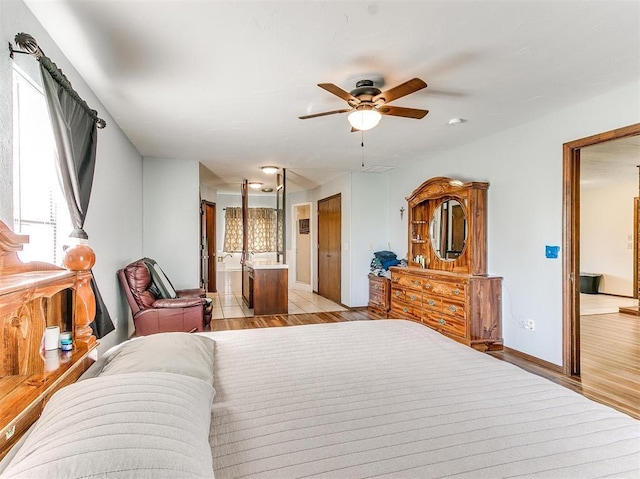 bedroom featuring connected bathroom, ceiling fan, light hardwood / wood-style floors, and multiple windows