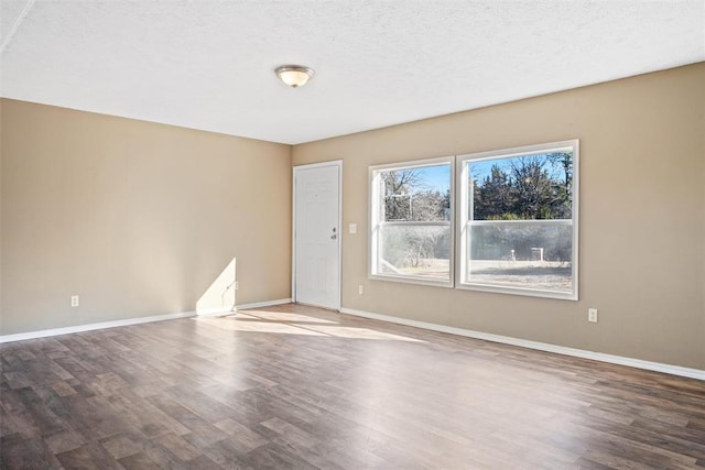 unfurnished room with a textured ceiling and dark wood-type flooring