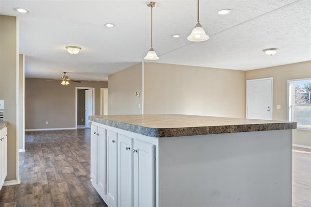 kitchen featuring dark hardwood / wood-style flooring, ceiling fan, pendant lighting, white cabinets, and a kitchen island