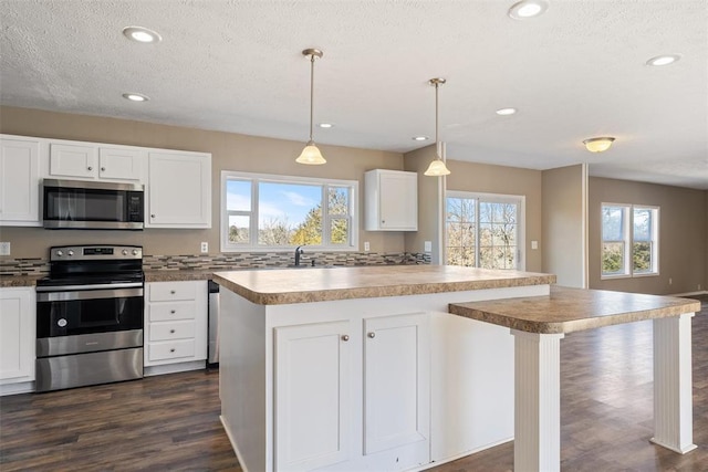 kitchen featuring pendant lighting, a center island, dark hardwood / wood-style floors, white cabinetry, and stainless steel appliances