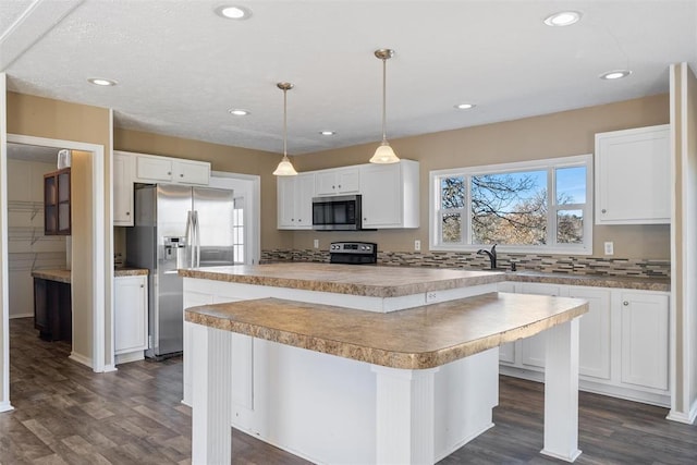 kitchen featuring white cabinets, appliances with stainless steel finishes, a center island, and a breakfast bar area