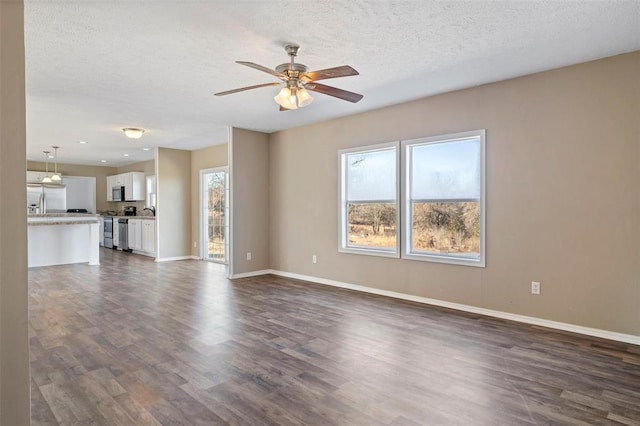 unfurnished living room with dark hardwood / wood-style flooring, a textured ceiling, and ceiling fan