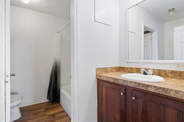 full bathroom featuring vanity, shower / bath combo, hardwood / wood-style flooring, toilet, and a textured ceiling