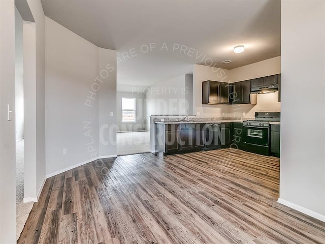 kitchen with light stone countertops, sink, dishwasher, black gas range oven, and hardwood / wood-style flooring