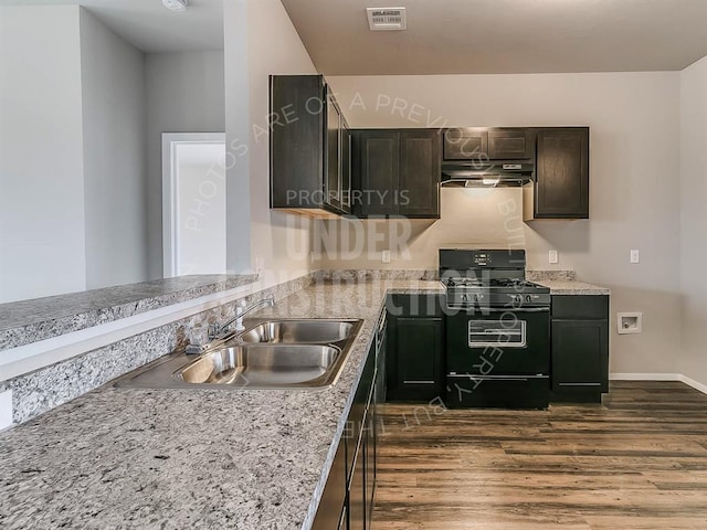 kitchen with dark brown cabinetry, sink, dark wood-type flooring, black gas range oven, and light stone counters