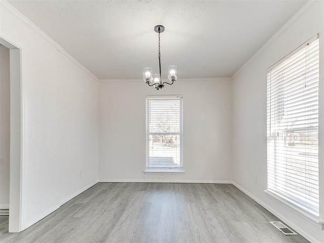 spare room with a notable chandelier, light wood-type flooring, and crown molding