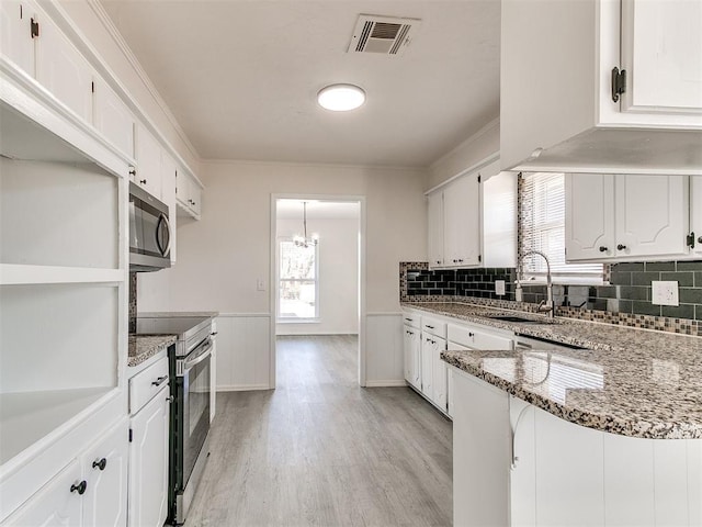 kitchen with white cabinetry, sink, stainless steel appliances, dark stone countertops, and light hardwood / wood-style floors