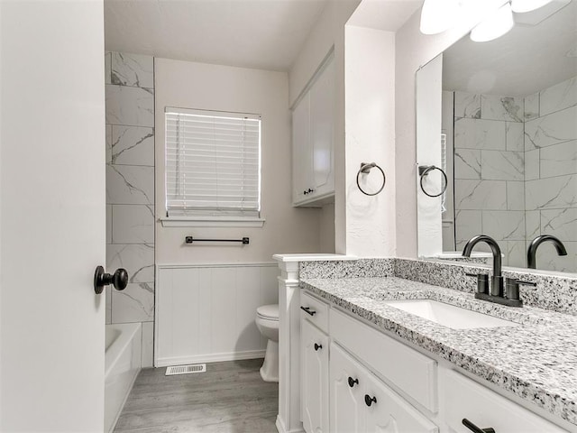 full bathroom featuring hardwood / wood-style flooring, shower / washtub combination, vanity, and toilet