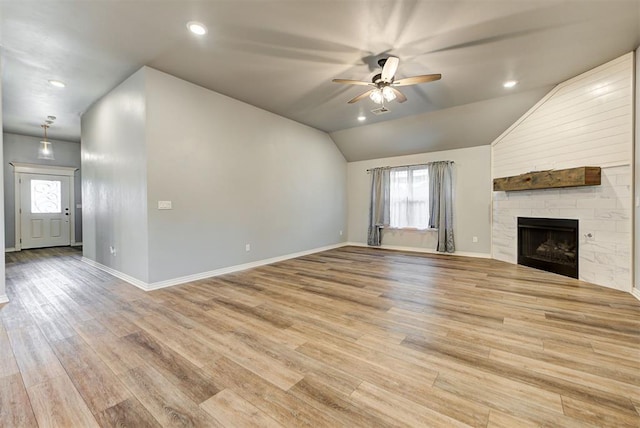 unfurnished living room with ceiling fan, a fireplace, vaulted ceiling, and light hardwood / wood-style flooring