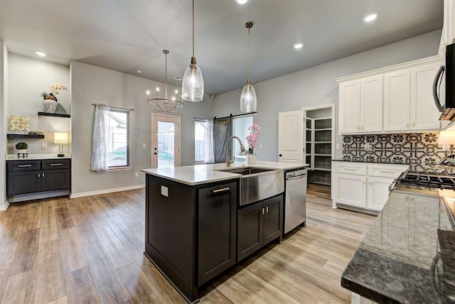 kitchen with white cabinetry, hanging light fixtures, stainless steel dishwasher, and a barn door