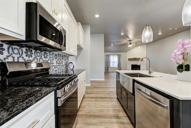 kitchen featuring white cabinetry, dark stone countertops, pendant lighting, ceiling fan, and stainless steel appliances