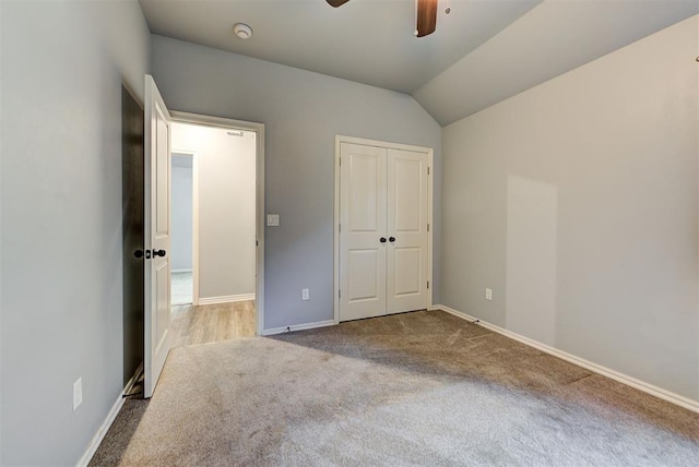 unfurnished bedroom featuring ceiling fan, lofted ceiling, a closet, and light carpet