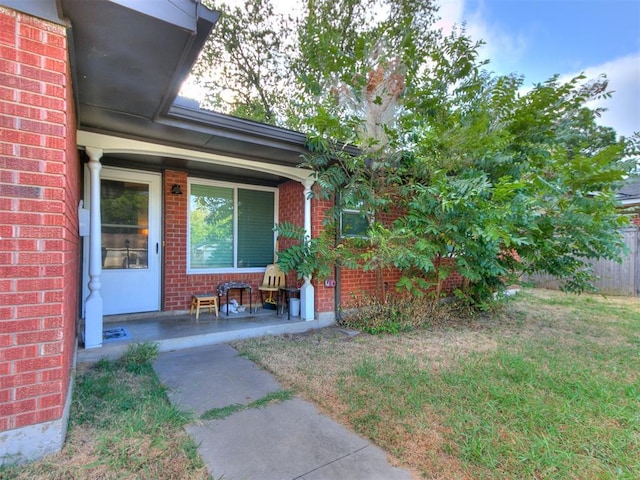 property entrance featuring a lawn and covered porch