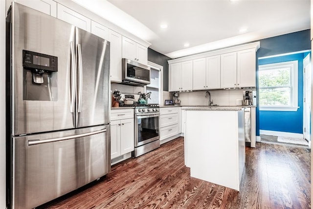 kitchen with white cabinetry, dark hardwood / wood-style floors, an island with sink, and appliances with stainless steel finishes