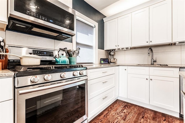 kitchen featuring dark hardwood / wood-style floors, decorative backsplash, white cabinetry, appliances with stainless steel finishes, and sink