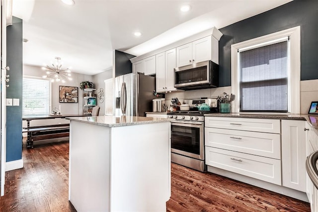 kitchen with white cabinets, a center island, an inviting chandelier, dark hardwood / wood-style floors, and appliances with stainless steel finishes