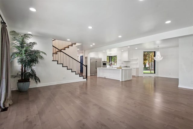 unfurnished living room featuring recessed lighting, baseboards, dark wood-style flooring, and stairs