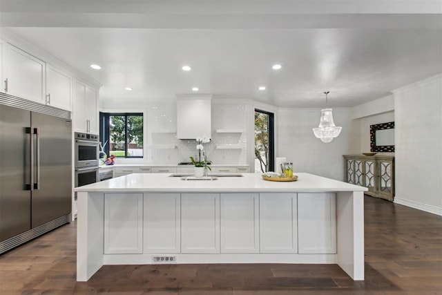 kitchen with white cabinets, decorative light fixtures, an island with sink, and appliances with stainless steel finishes