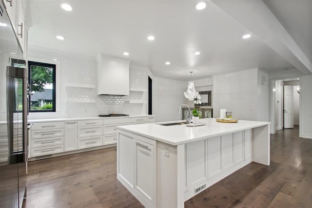 kitchen with sink, hanging light fixtures, dark hardwood / wood-style floors, a center island with sink, and white cabinets