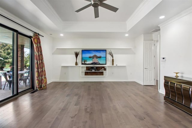 unfurnished living room featuring baseboards, wood finished floors, a tray ceiling, and ornamental molding