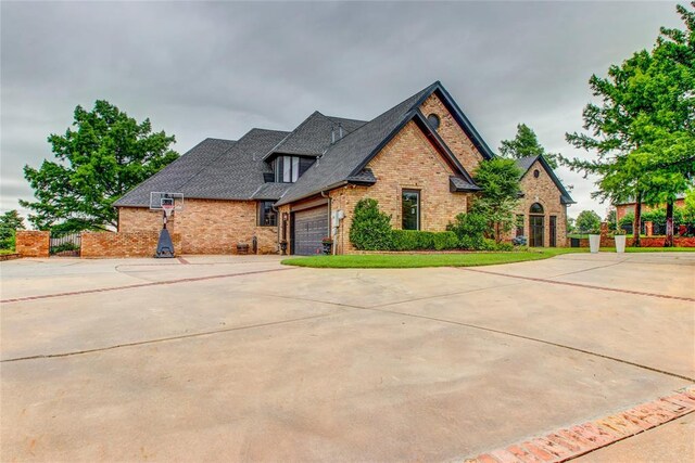 5801 Oak Tree Rd, Edmond, OK 73025 - view of front of home with brick siding, an attached garage, driveway, and a shingled roof