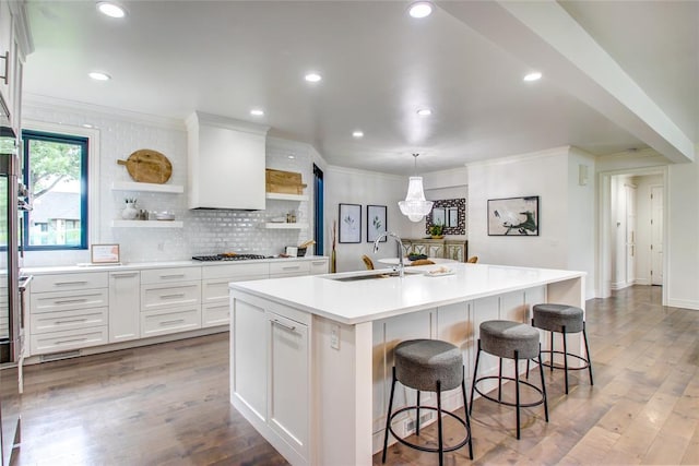 5801 Oak Tree Rd, Edmond, OK 73025 - kitchen featuring open shelves, stainless steel gas stovetop, crown molding, a kitchen island with sink, and white cabinets