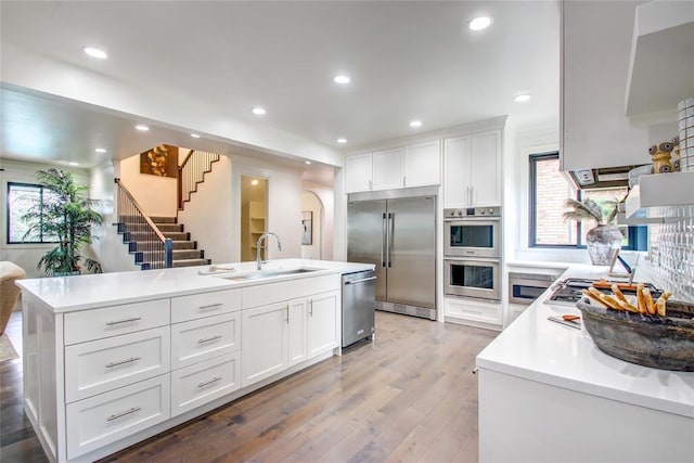 5801 Oak Tree Rd, Edmond, OK 73025 - kitchen with appliances with stainless steel finishes, light wood-style flooring, light countertops, white cabinets, and recessed lighting