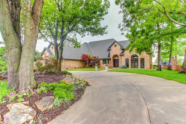 5801 Oak Tree Rd, Edmond, OK 73025 - view of front of property with brick siding, a front lawn, curved driveway, roof with shingles, and stone siding