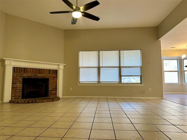 unfurnished living room with a brick fireplace, ceiling fan, and light tile patterned flooring