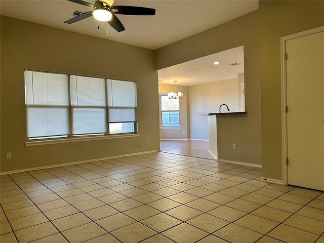 empty room with light tile patterned flooring and ceiling fan with notable chandelier