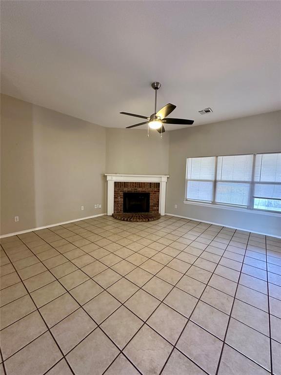 unfurnished living room with ceiling fan, light tile patterned flooring, and a fireplace