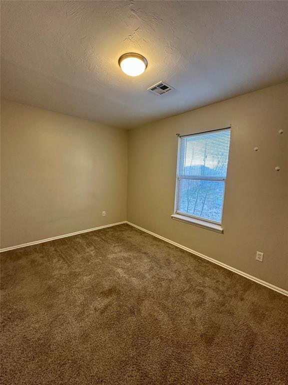 empty room with carpet and a textured ceiling